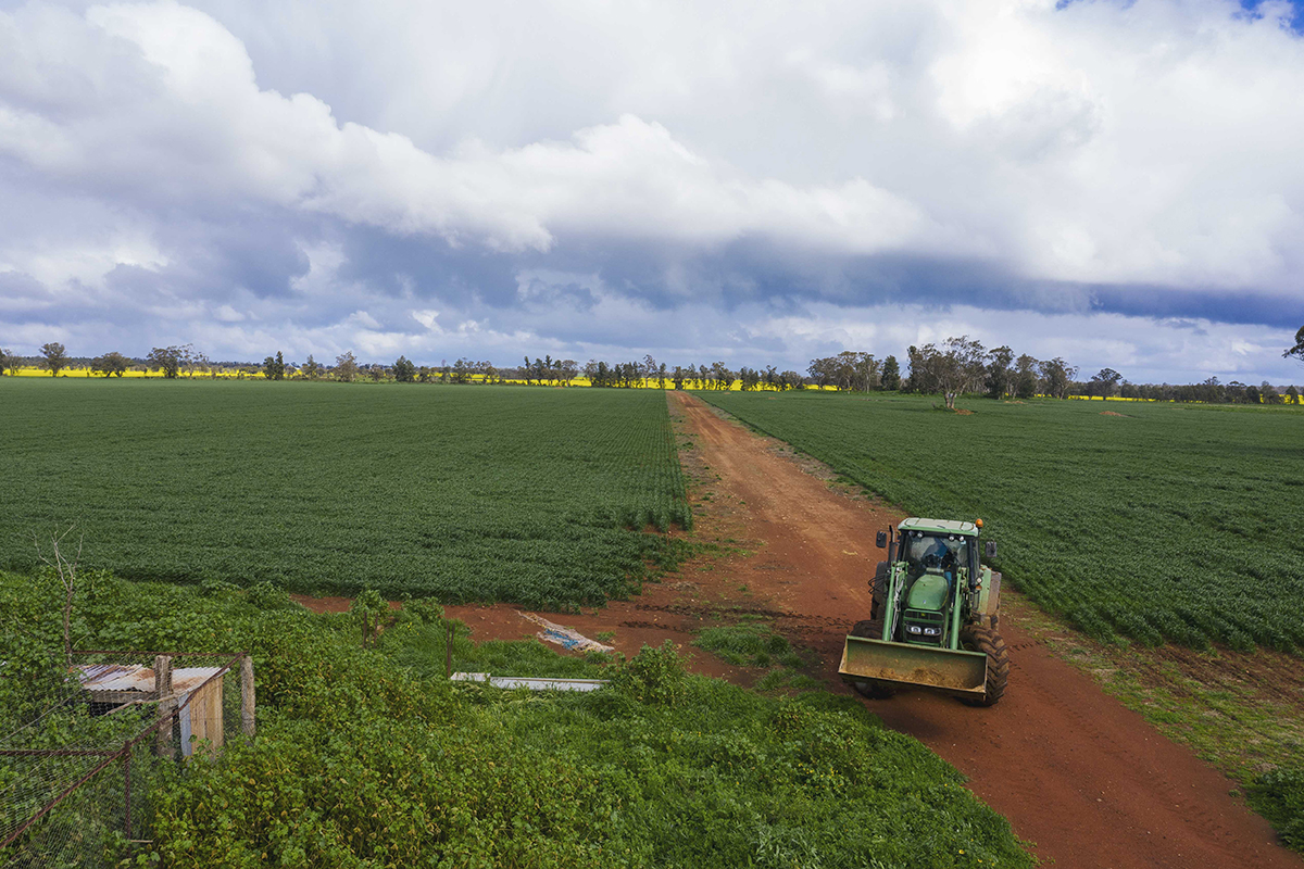 A landscape view of a tractor on a dirt road with a cloudy sky in Parkes
