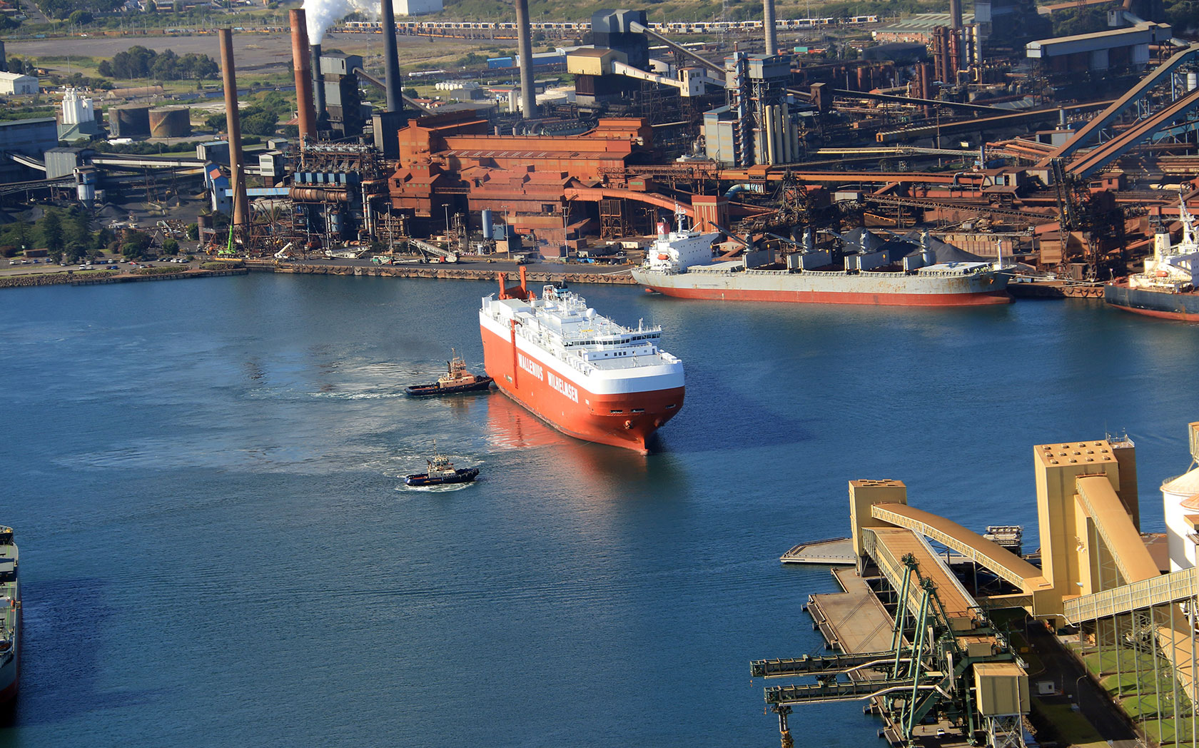 An aerial view of a boat leaving the harbour at Port Kembla 