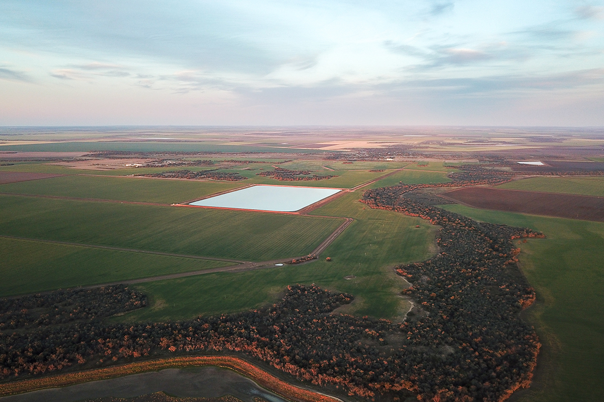 Aerial view of a colourful sky as the sun sets over green land