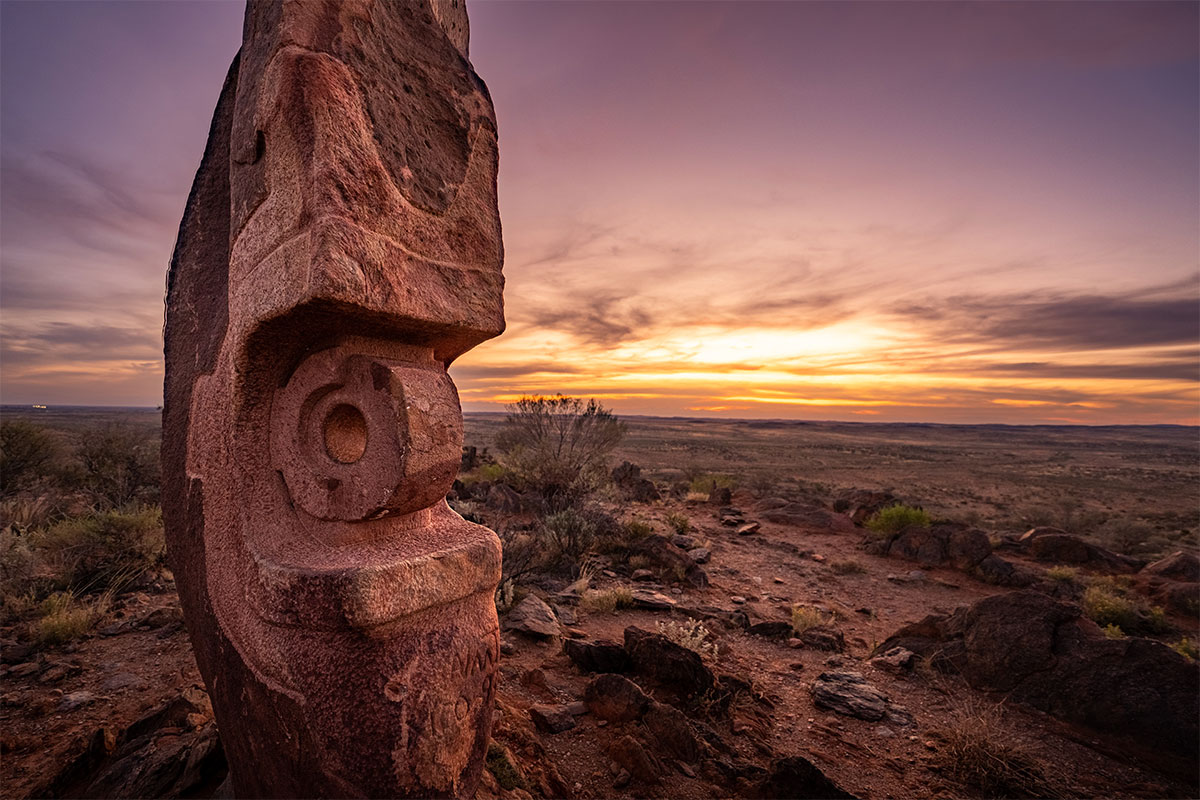 The Living Desert sculpture in the foreground with an orangey-pink sunset in the background