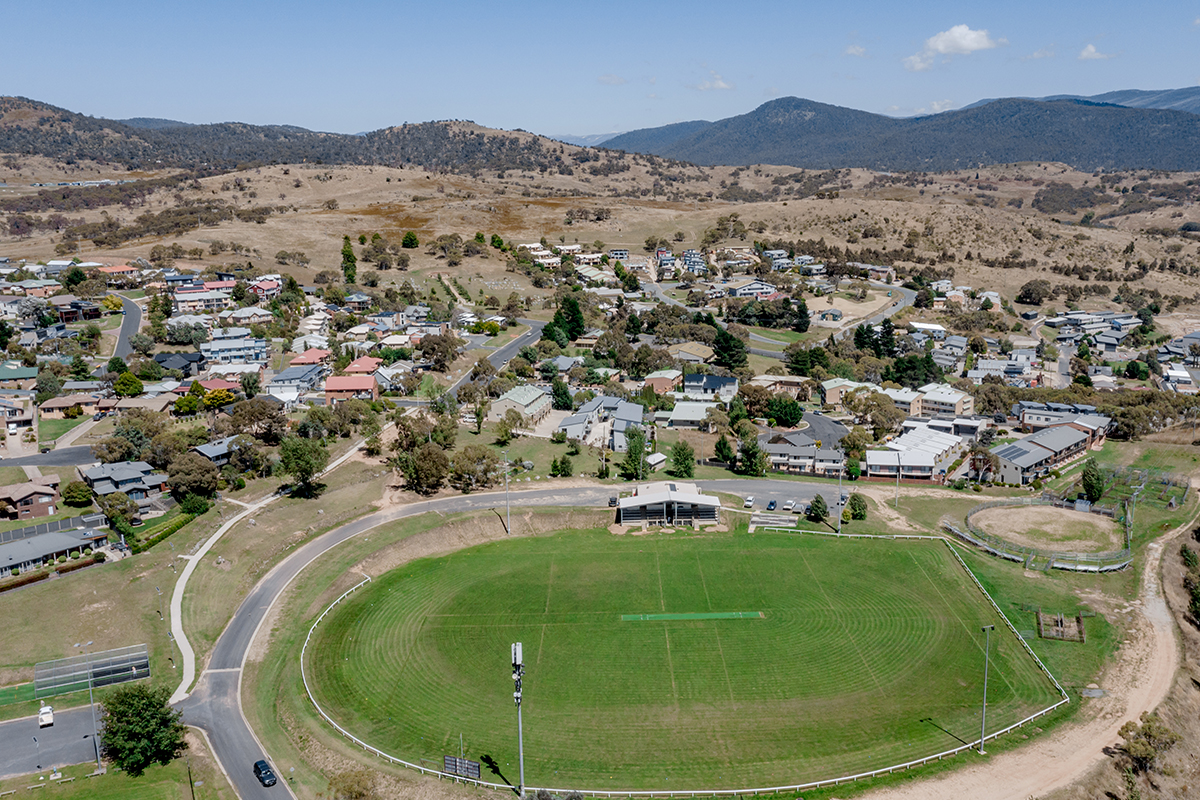 Aerial view of Jyndabyne include houses and a sports oval with mountains in the background